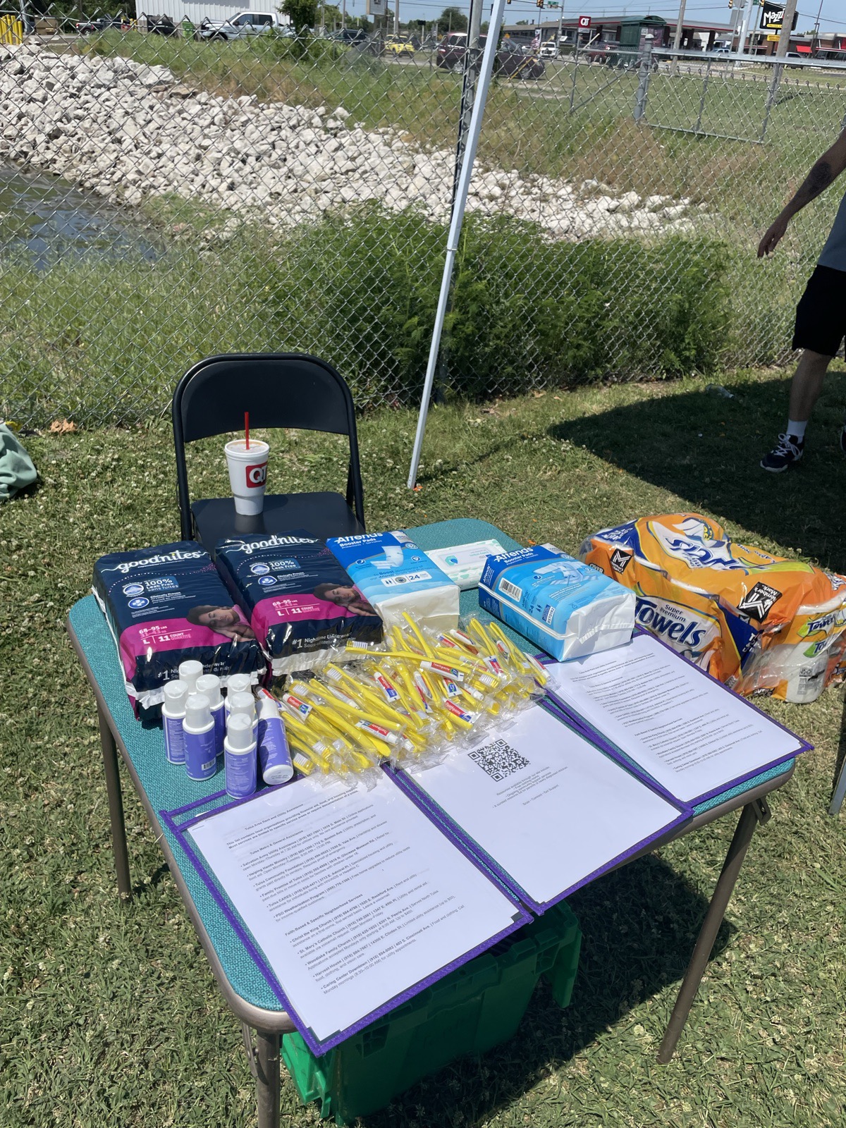 An outdoor pop-up resource table with diapers, hygiene supplies, and informational handouts