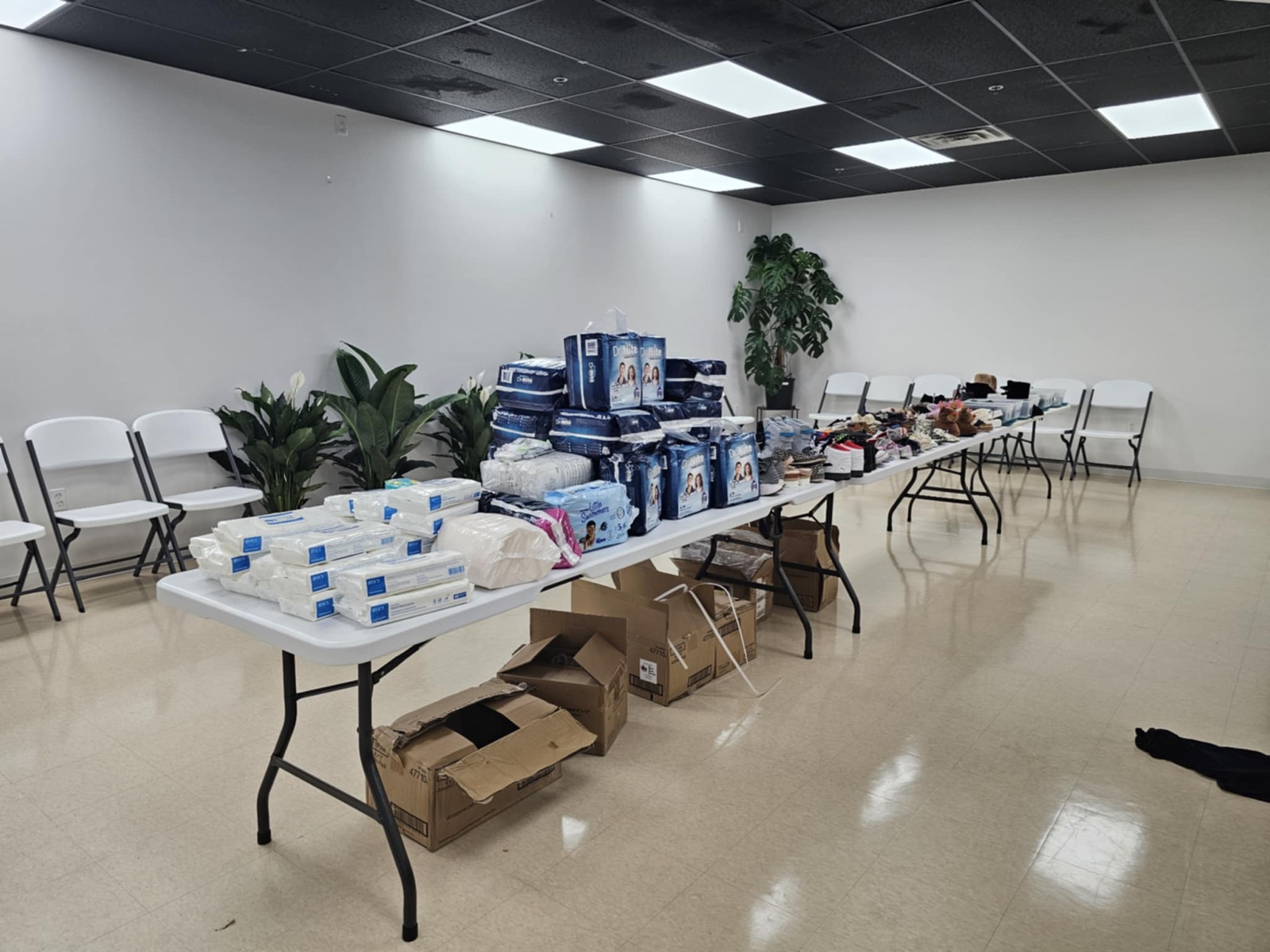 Tables lined with diapers, wipes, and household supplies set out for a community distribution
